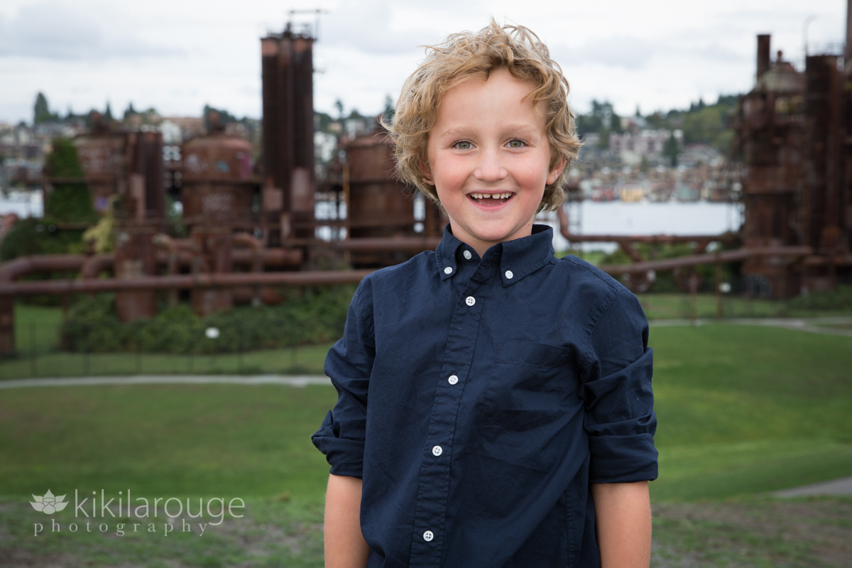 Young boy smiling in blue button down shirt in front of industrial site Seattle