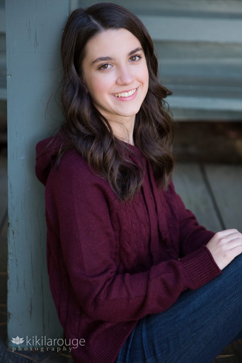 Portrait of teen girl in maroon sweater on porch