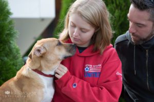 Feist puppy rescue dog with foster parents on stone wall