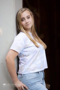 Blonde girl senior portraits leaning on barn door