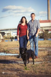Couple in jeans with black rescue dog on leash