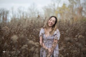 Girl in field with with pastel purple dress smiling