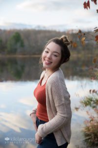 Girl with hair up in bun by pond at sunset