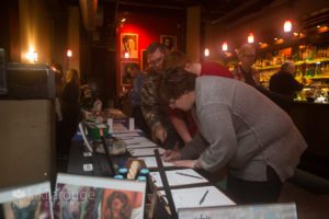 Woman in gray sweater signing up for a silent auction item at dog benefit