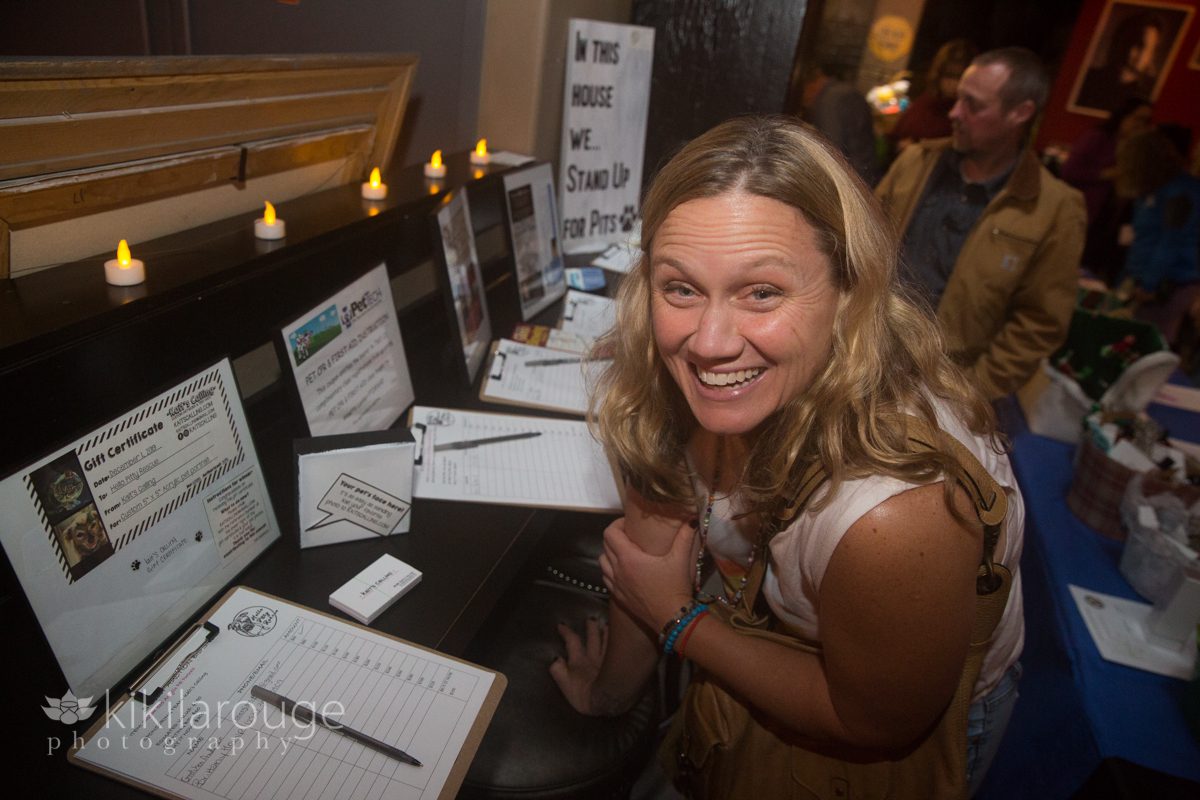 Blonde woman smiling in front of silent auction item signup forms