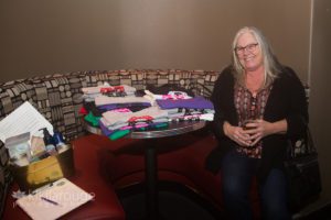Woman sitting in booth with rescue dog tee shirts