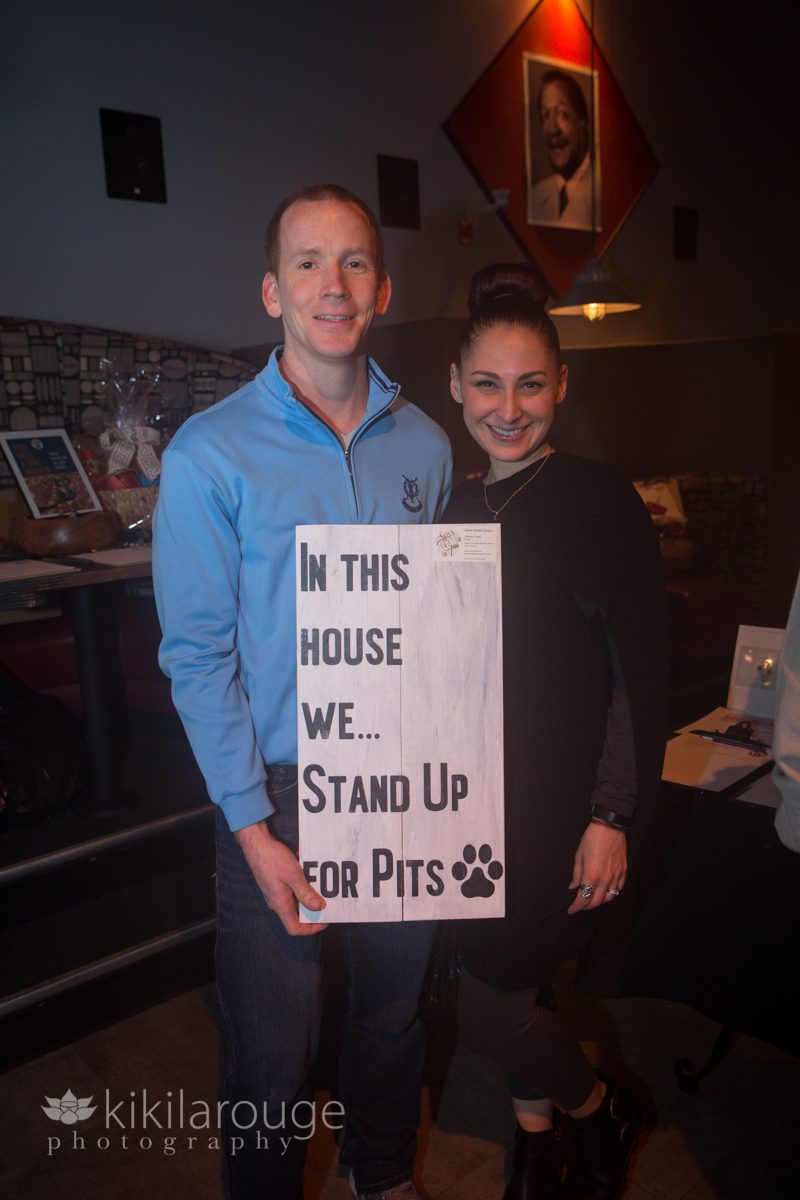 Couple holding winning auction item at Stand Up for Pits fundraiser