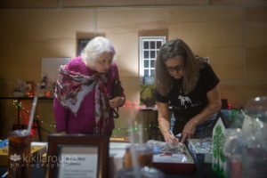 Two women looking and signing up to win silent auction items at dog benefit