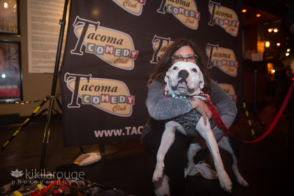 Woman hugging a little white pit bull mix dog at Tacoma Comedy Club