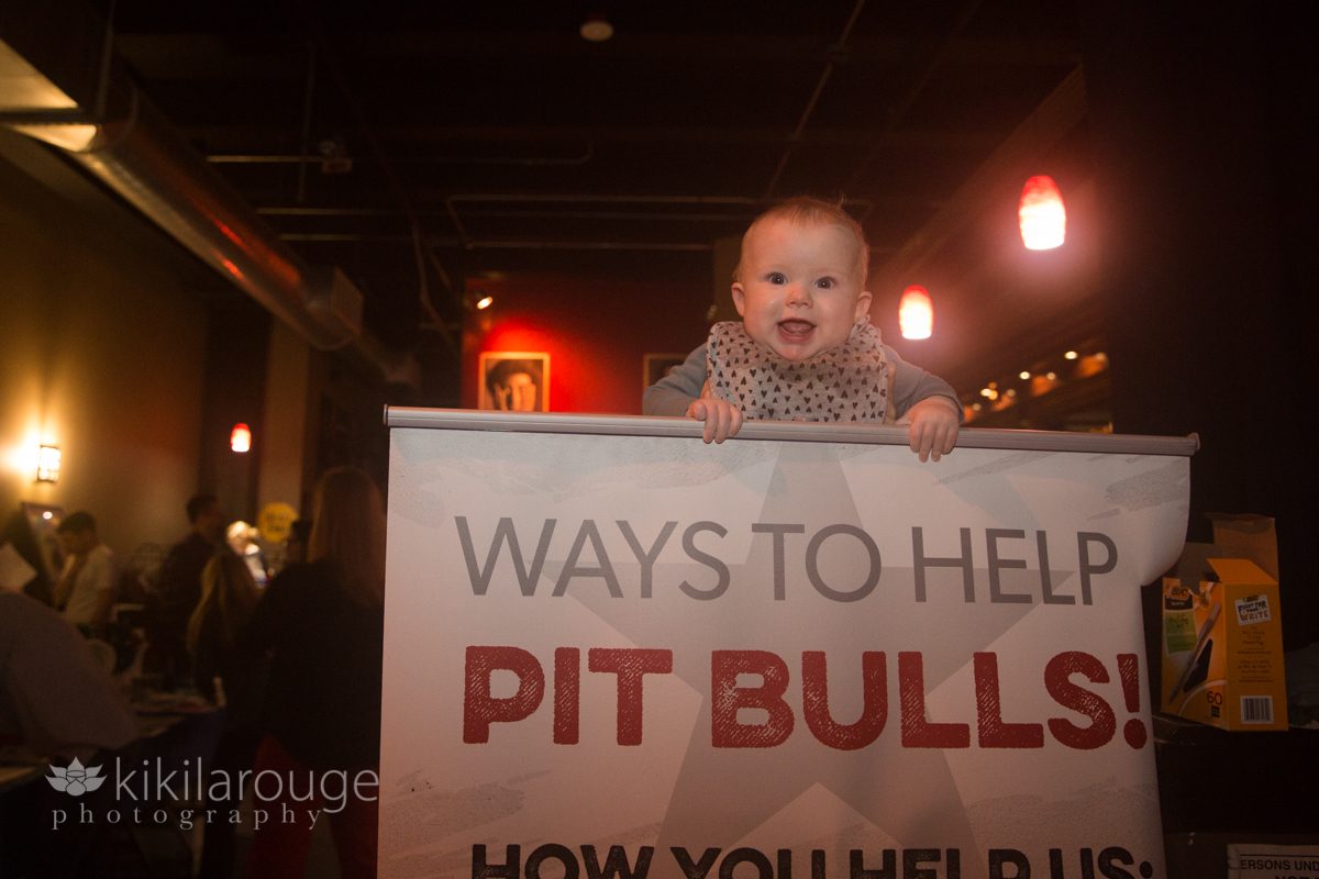 Little baby popping up behind sign Ways To Help Pit Bulls