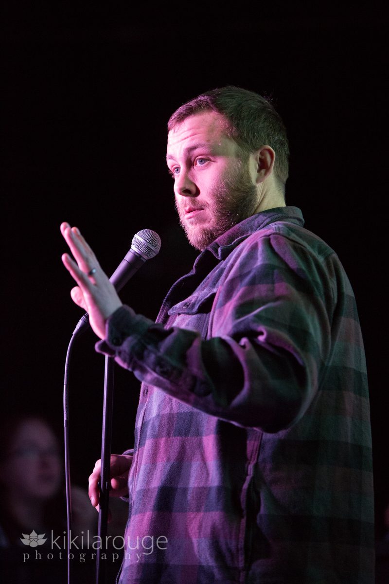 Comedian telling joke on stage in flannel shirt