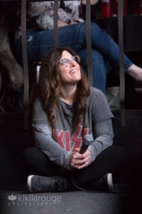 Woman smiling looking up at screen with KISS shirt on