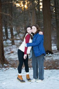 Sister hugging in park with sunset in background