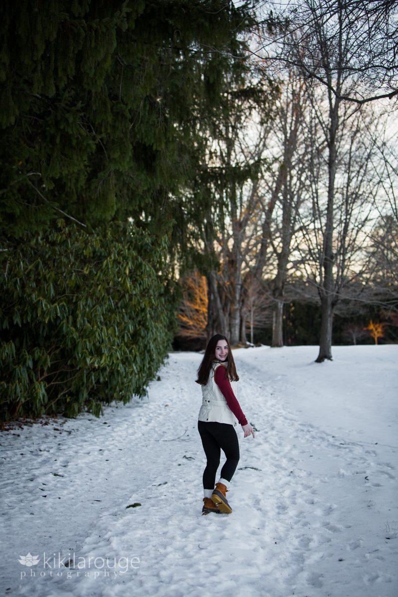 Teen girl walking down snowy path into woods