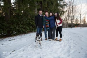 Family laughing in backdrop with their Boston Terrier in focus in front