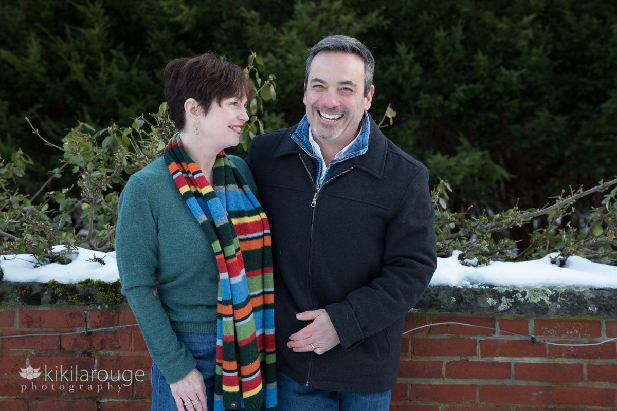 Couple laughing in park by brick wall