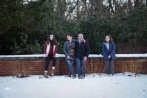 Family sitting on snowy brick wall in Maudslay Park