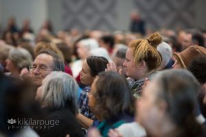 Two women in a crowd listening to a speaker