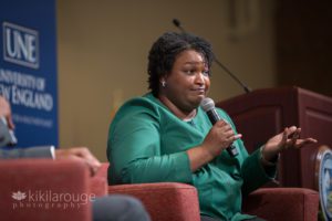 Stacey Abrams in green top with microphone shrugging