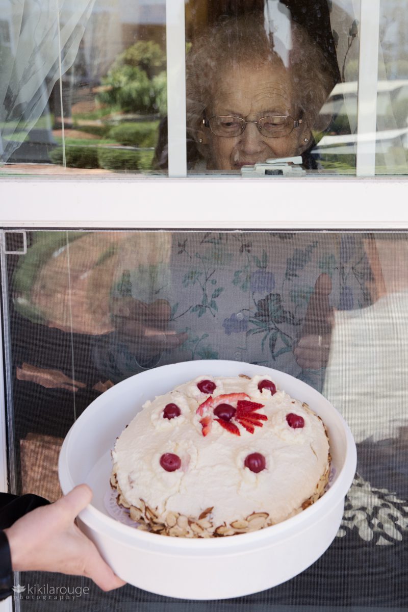 A rum cake next to a window with elderly woman smiling