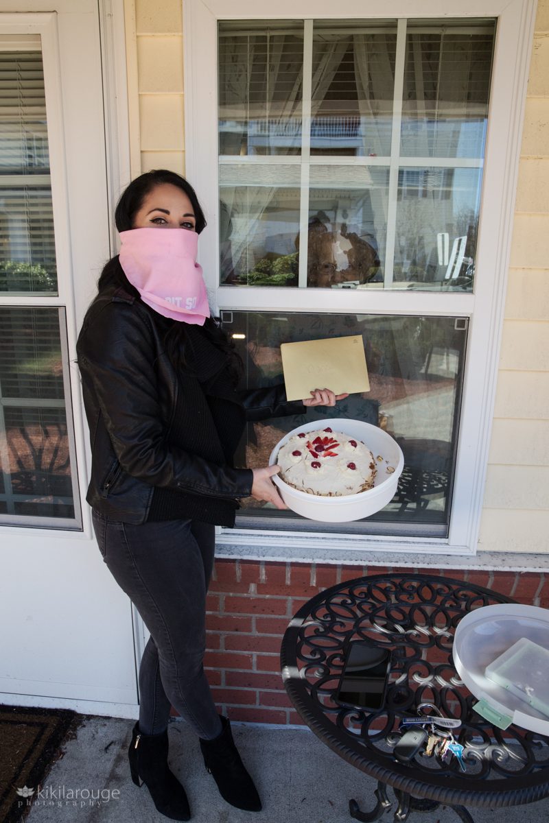 Woman holding a birthday cake and card for her grandmother's bday at window