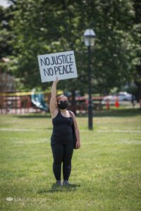 One woman in black holding "No Justice No Peace" sign