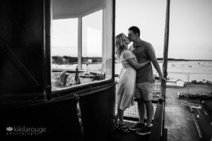 Young couple kissing on top of Newburyport lighthouse with river in distance