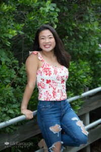 Girl in red and white top with jeans leaning on railing