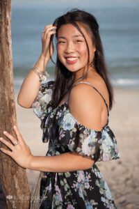 Teen girl portrait in long black dress by driftwood at Sandy point