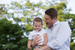 Dad and toddler son laughing at beach