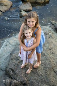 two girls standing on rock in tidepool