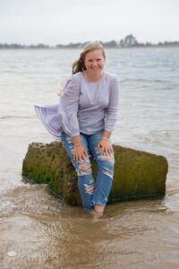 Girl sitting by water's edge in extreme wind