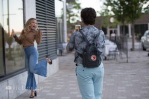 Boy in blue taking an iPhone photo of girl kicking up heals