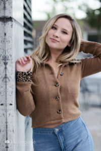 Blonde girl brown seater on marble wall
