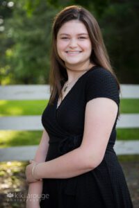 Brunette teen girl senior portrait by white fence