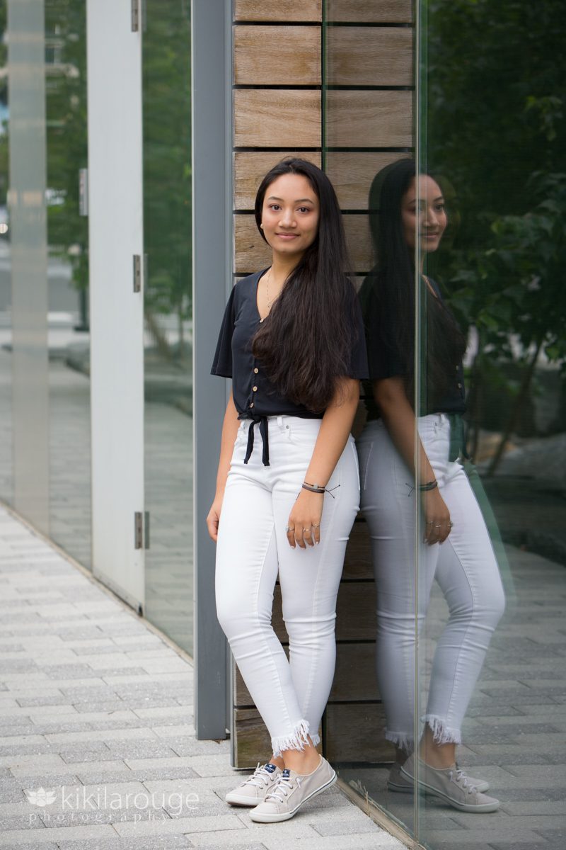 Full body portrait of teen girl in white pants against ICA building glass