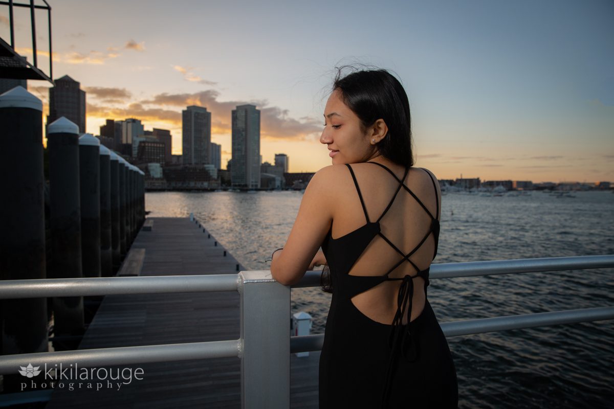 Profile view of girl leaning on railing at Boston Harbor sunset