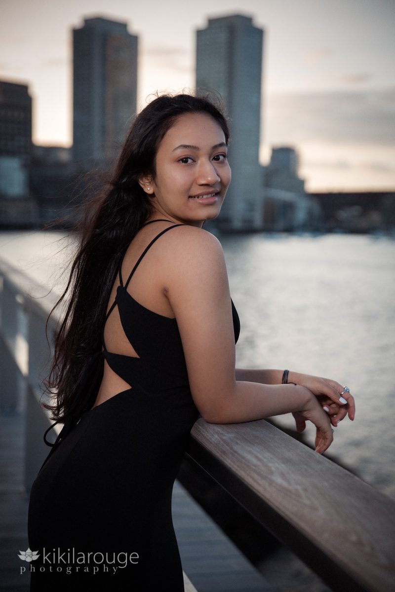 Sunset portrait of girl in black prom dress Boston looking over shoulder