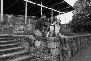 Couple with their dog on stone wall giving kisses