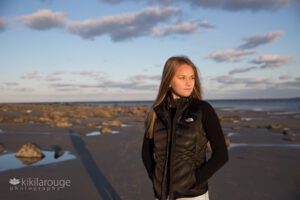 Girl on open beach at sunset with black vest and long shadow