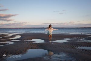 Girl running down open beach with tidepools towards ocean
