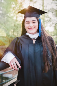 Woman long dark hair in cap in gown with sun glare on bridge