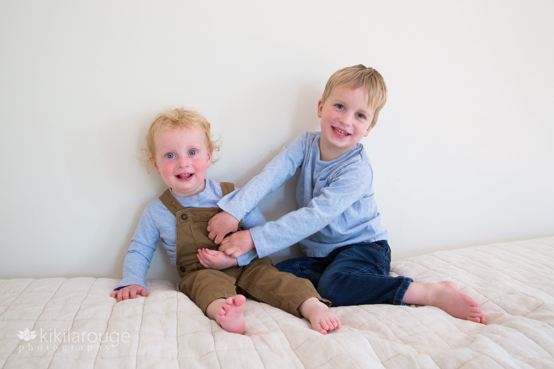 Two little boys tickling and playing on bed