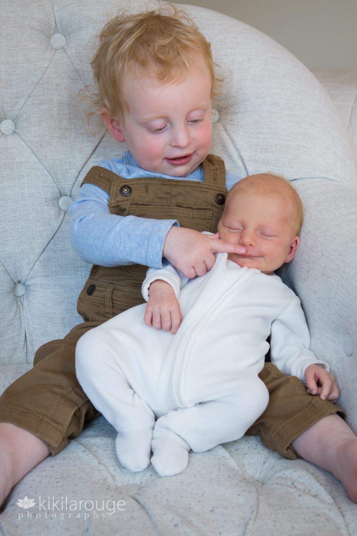 Toddle boy in brown overalls with newborn baby sister