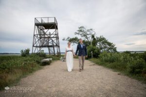 Wedding couple walking on sand path with viewing tower in backdrop