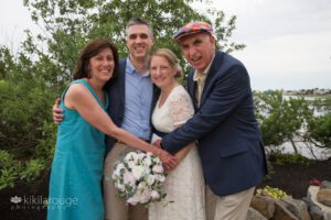 Mom and Dad of groom hugging the newly married couple
