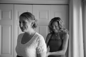 Mom tying sash on back of bride's wedding dress