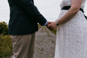 Couple holding hands close up on long dirt path