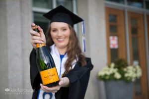 Girl in cap and gown holding out Veuve Cliquot