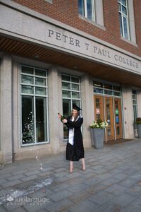 Girl in cap and gown popping a bottle of champagne